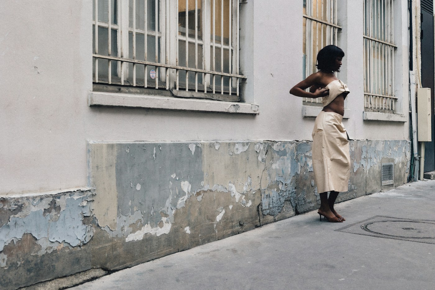 Woman wearing a cream outfit beside a weathered building