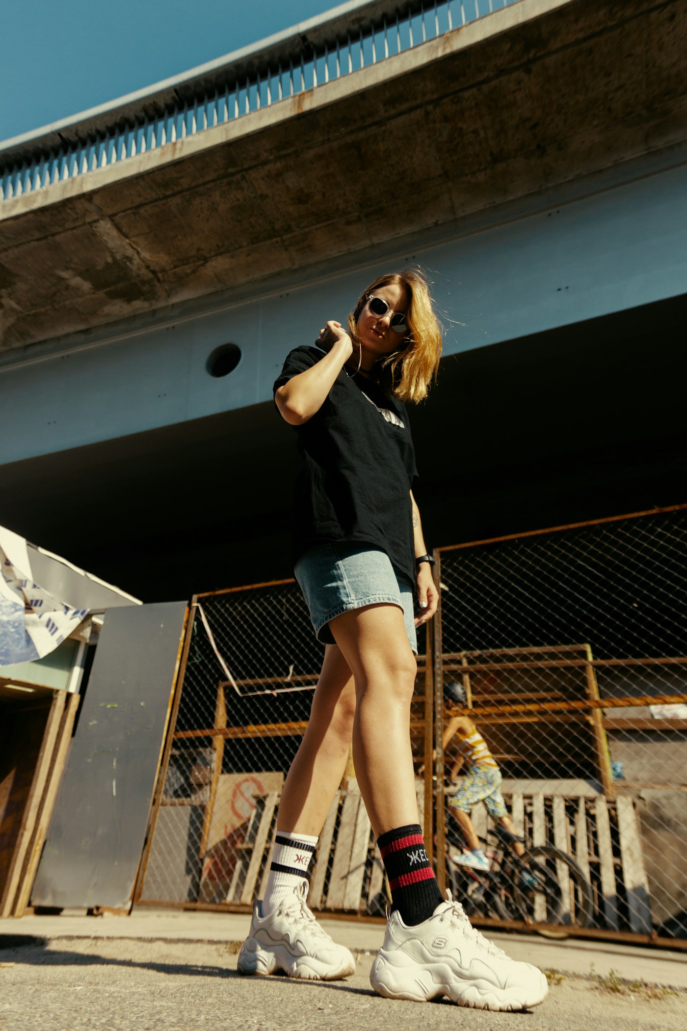 Woman wearing casual streetwear and sneakers beneath a bridge