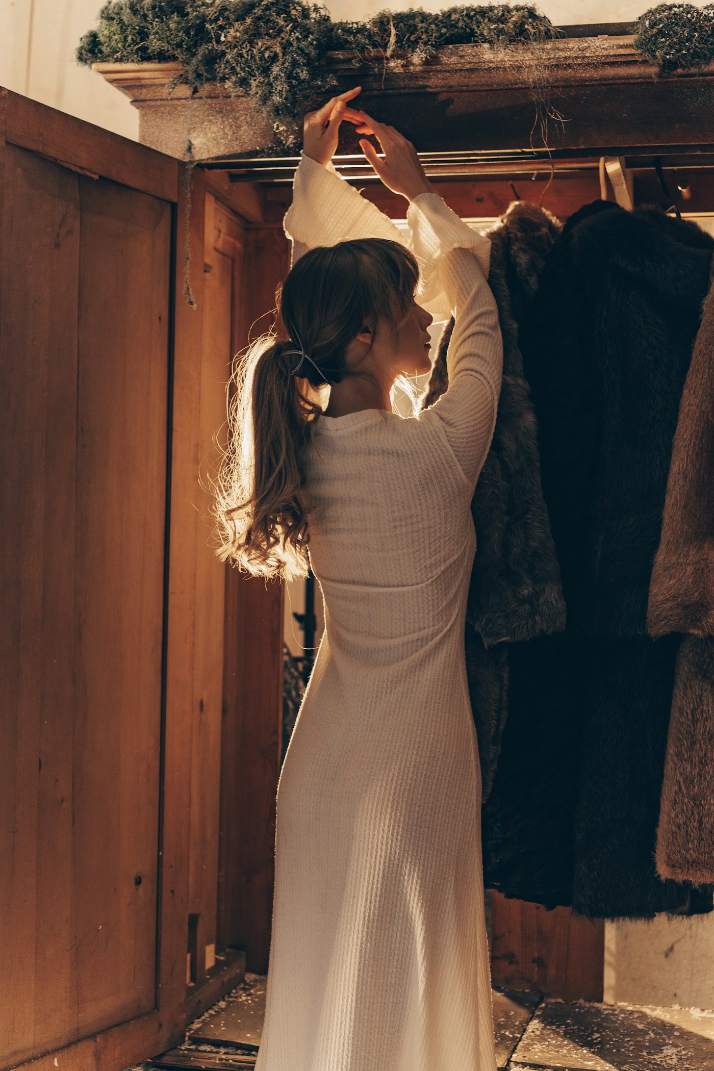 Woman selecting clothing from a wooden wardrobe