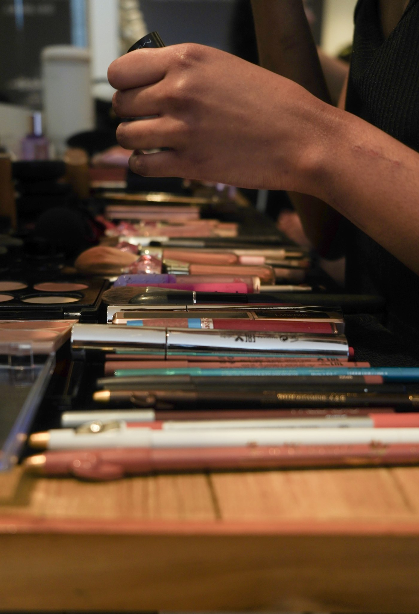 Hands arranging cosmetics and brushes on a table