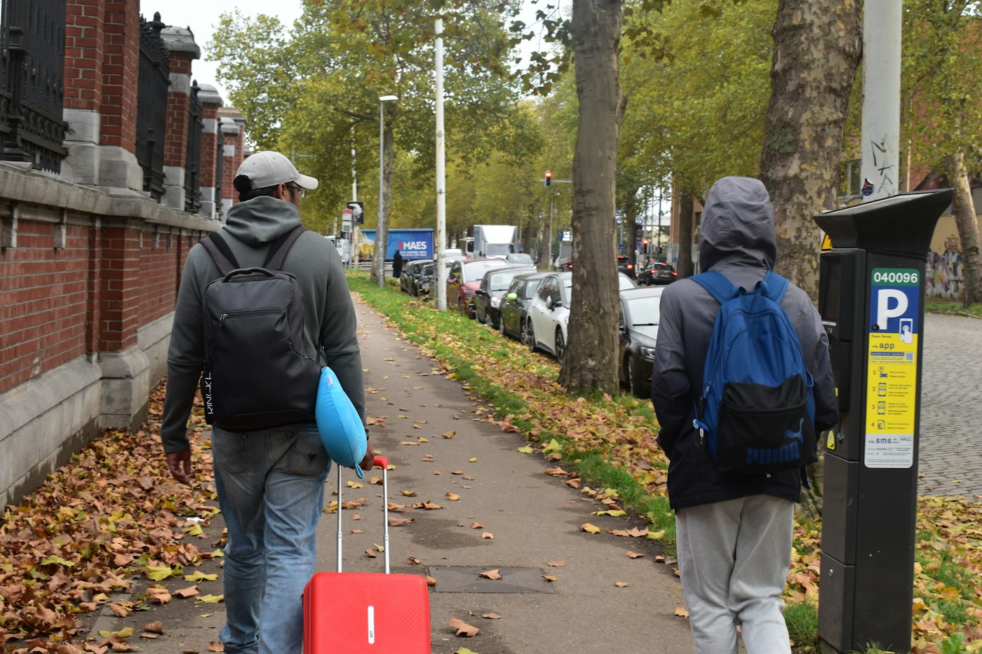Two travelers walking along a sidewalk with luggage